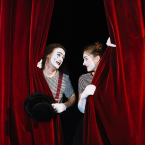 Deux comédiens joyeux derrière un rideau de théâtre rouge flamboyant